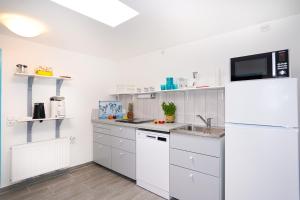 eine weiße Küche mit Spüle und Kühlschrank in der Unterkunft Haus Marienfeld Bungalow "Marcel" in Grömitz + 12 Fotos
