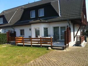 a house with a wooden fence in front of it at Ferienwohnung Wede in Ueckeritz