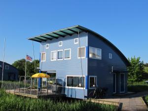 a large blue house with a yellow roof at Ferienhaus SEABIRD by FeWo-PLAN OOST150 mit direktem Zugang ins LAUWERSMEER in Anjum