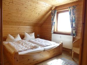 哈瑟尔费尔德Ferienhaus Nr 23, Typ A, Ferienanlage Blauvogel, Hasselfelde, Harz的木制客房的一张床位,设有窗户 更多11张照片