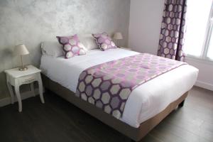 - une chambre dotée d'un grand lit avec des oreillers roses et violets dans l'établissement Cosy Apparts Suresnes La Défense, à Suresnes