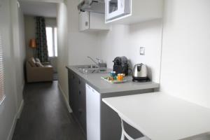 a white kitchen with a counter and a sink at Cosy Apparts Suresnes La Défense in Suresnes