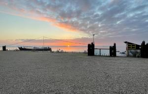 a sunset on the beach with a boat in the water at Stunning Ship In Biddinghuizen in Biddinghuizen