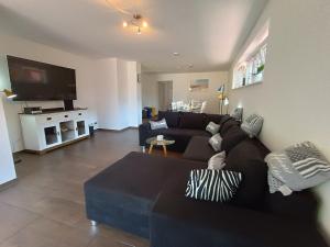 a living room with a black couch and a tv at Ferienhaus in der Schleife 2 in Rendsburg in Rendsburg