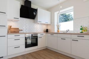 a white kitchen with white cabinets and a sink at Küstenbutze im modernen Scandi-Style mit Garten und Terrasse in Mildstedt