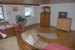 ein Wohnzimmer mit Tisch und Fernseher in der Unterkunft Ferienhaus, Bauernhof mit Angel- und Badesee, Roßhaupten, Allgäu in Roßhaupten