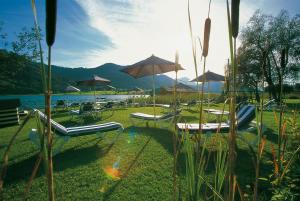a group of tables and chairs with umbrellas and water at Seehotel Enzian in Weissensee