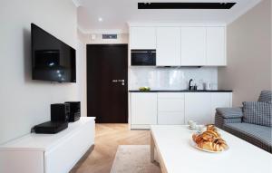 eine Küche und ein Wohnzimmer mit weißen Schränken und einem Tisch in der Unterkunft 1 Bedroom Gorgeous Apartment In Gdansk in Danzig