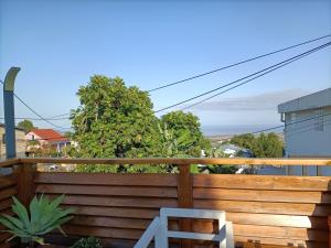 a wooden deck with a bench on a balcony at Chambre cosy in Saint-Paul