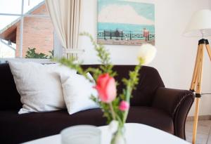 ein Wohnzimmer mit einer Couch und einem Tisch mit Blumen in der Unterkunft Bauernhof Höper-Rauert - Reihenhaus 8 in Neujellingsdorf