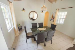 a dining room with a glass table and chairs at Sweet Home Grenada Caribbean in Lance aux Épines