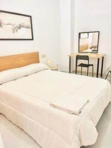 una camera da letto con un grande letto bianco e un tavolo di PISO CENTRO HISTÓRICO 3 DORMITORIOS a Jerez de la Frontera