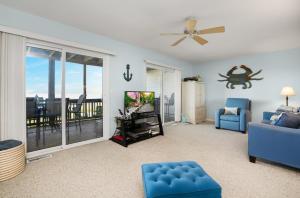 un salon avec un canapé bleu et une télévision dans l'établissement Blue Chair Bay - Waterfront townhome with Fishing pier!, à Black Point Landing