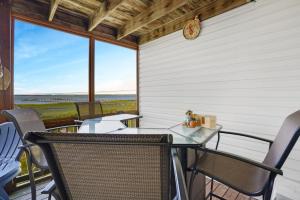 d'un balcon avec une table, des chaises et une horloge. dans l'établissement Blue Chair Bay - Waterfront townhome with Fishing pier!, à Black Point Landing