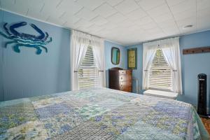 a blue bedroom with a bed and two windows at Bue Crab Bungalow - Charming in-town cottage! in Birch Town