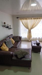 a living room with a leather couch and a window at Apartamento amplio y lujoso in Mocoa