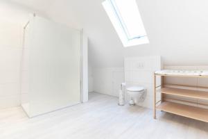 a white bathroom with a toilet and a skylight at Ferienwohnung 140 qm OstfrieslandNordsee für 1-6 Personen - Südbrookmerland in Südbrookmerland