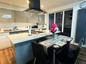 a kitchen with a table with a vase of flowers on it at Elevate your stay with Sai home in West Thurrock