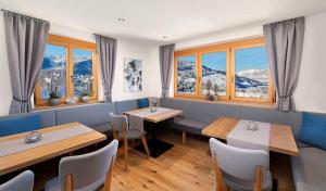 a restaurant with tables and chairs and snow covered mountains at Der Sonnenhof - Appartement Steinbergstein in Westendorf