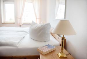 ein Bett mit einer Lampe und einem Buch auf einem Tisch in der Unterkunft Bauernhof Höper-Rauert - Reihenhaus 6 in Neujellingsdorf + 16 Fotos
