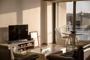 a living room with a flat screen tv on a table at Seafront condo with a view of Valletta in Il-Gżira taʼ Forti Manoel
