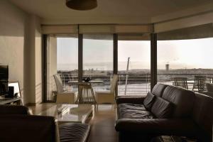 a living room with a couch and a large window at Seafront condo with a view of Valletta in Il-Gżira taʼ Forti Manoel