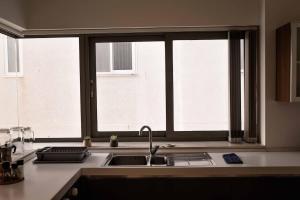 a kitchen with a sink and two windows at Seafront condo with a view of Valletta in Il-Gżira taʼ Forti Manoel