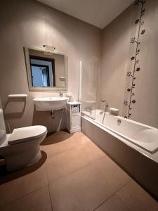 a bathroom with a toilet and a tub and a sink at Seafront condo with a view of Valletta in Il-Gżira taʼ Forti Manoel