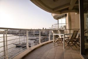 a balcony with a table and chairs on a ship at Seafront condo with a view of Valletta in Il-Gżira taʼ Forti Manoel