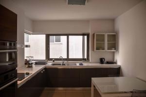 a kitchen with a sink and a large window at Seafront condo with a view of Valletta in Il-Gżira taʼ Forti Manoel