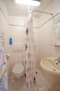 Un baño con inodoro, lavabo y cortina de ducha. en Ferienbungalow 4, en Dahme