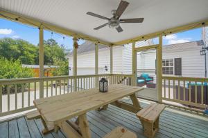 einen Picknicktisch aus Holz auf einer Terrasse mit einem Deckenventilator in der Unterkunft Capeville Cottage - modern comfort close to Cape Charles! in Cape Charles
