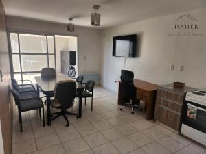 a living room with a table and chairs and a television at Daher Apartment Homes in La Consulta