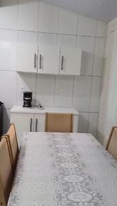 une cuisine avec une table, des chaises et des armoires blanches dans l'établissement Casa Fundos na Enseada - 2 Quartos, à São Francisco do Sul