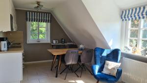 a kitchen with a wooden table and two blue chairs at Wohnung Ankerplatz in Wrixum