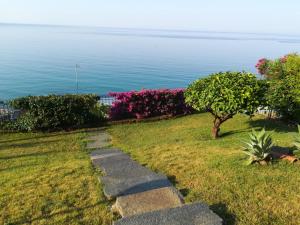 a stone path leading to the ocean with flowers at Mare e Relax - Il Villino ai Tre Ponti - Monolocale in Sanremo