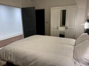 une chambre avec un grand lit blanc et un miroir dans l'établissement Luxury Garden Flat London, à Bexleyheath 3 autres photos