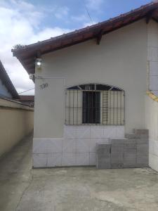 a white building with a barred window on it at Casa com piscina Mongaguá 2 quartos in Mongaguá