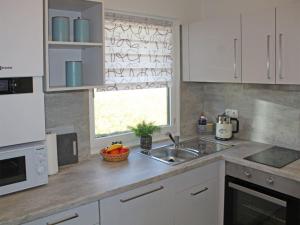 une cuisine avec des armoires blanches, un évier et une fenêtre dans l'établissement Ferienhaus Nr 134, Kategorie Komfort, Feriendorf Hochbergle, Allgäu, à Lechbruck am See