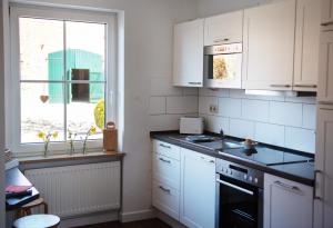 eine Küche mit weißen Schränken und einer Spüle und einem Fenster in der Unterkunft Bauernhof Höper-Rauert - Reihenhaus 1 in Neujellingsdorf