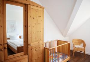 ein Schlafzimmer mit einem Kinderbett und einem Bett in einem Zimmer in der Unterkunft Bauernhof Höper-Rauert - Reihenhaus 1 in Neujellingsdorf + 12 Fotos