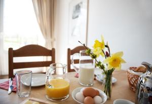 einen Tisch mit Orangensaft, Eiern und einer Blumenvase in der Unterkunft Bauernhof Höper-Rauert - Reihenhaus 2 in Neujellingsdorf