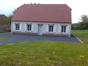 a small red and white house with a grass yard at Une virée à deux, gîte et spa in Guiscard