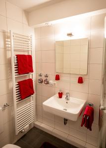 a white bathroom with a sink and red towels at Ferienapartment Blume in Meersburg