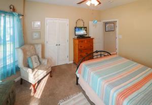 a bedroom with a bed and a chair and a television at Cockleshell Cottage - Pet friendly & Handicap Accessible! in Deep Hole