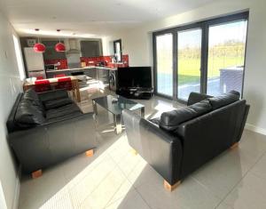 a living room with two leather couches and a glass table at Apple Lodge - Somerset Holiday Homes in North Wootton +15 photos