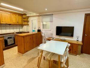 a kitchen with a white table and a television at Sol y playa in Puerto de Sagunto