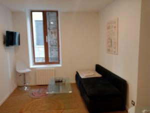 a living room with a black couch and a table at Sasha in Brive-la-Gaillarde
