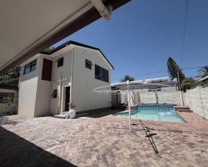a house with a swimming pool and an umbrella at Kabana Family Home and Guest House in Cape Town