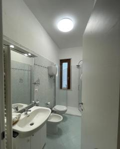 a white bathroom with a sink and a toilet at Casa Remolina in Montefollonico +13 photos